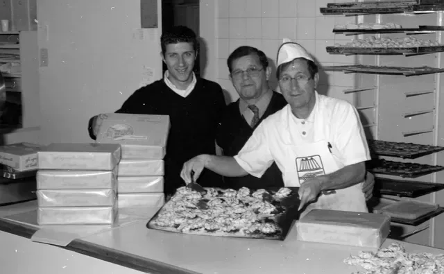Un uomo con un grembiule sta decorando una torta con la frutta